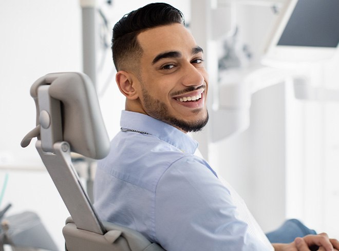 Smiling man holding Invisalign clear aligner