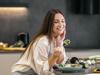 Woman in white sweater leaning against wall and smiling