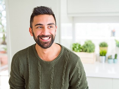 Man in green shirt smiling in kitchen