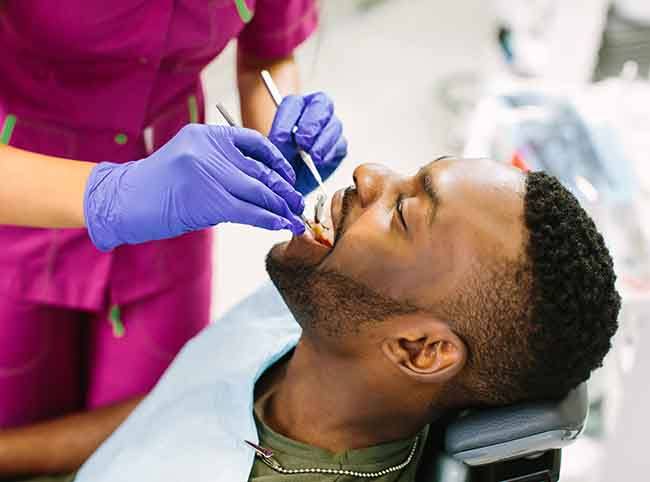 Man in green shirt and bib undergoing dental exam